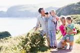 Family on cliffside path using binoculars and smiling