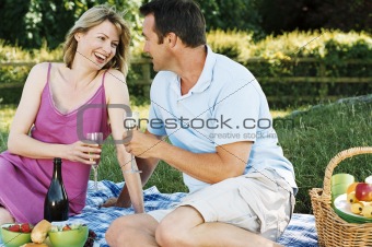 Couple sitting outdoors with picnic smiling