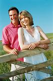 Couple standing outdoors by fence smiling