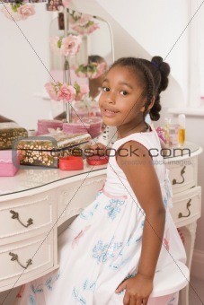 Young girl sitting at mirror in bedroom smiling