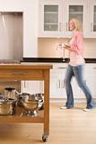 Woman walking in kitchen holding coffee