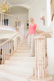 Woman coming down staircase in luxurious home