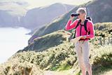 Woman on cliffside path using binoculars