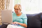 Woman in living room with laptop smiling
