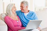 Couple in living room with laptop smiling