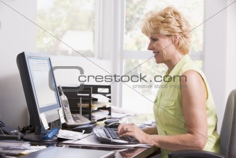 Woman in home office at computer smiling