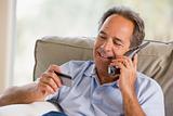 Man indoors using telephone and looking at credit card smiling