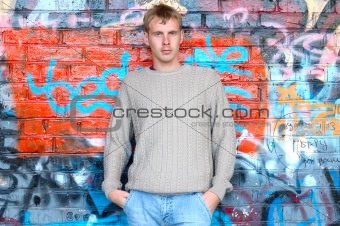 Young stylish man stand near graffiti brick wall.