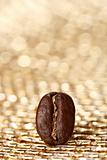 one coffee bean on golden glitter background