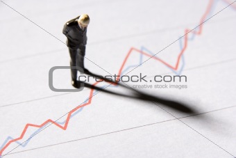 Figurine Of A Businessman Standing On A Line Graph