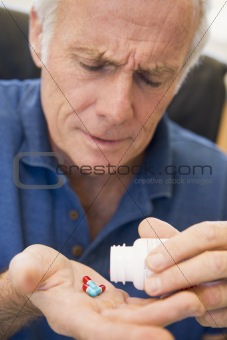 Senior Man Pouring Pills Out Of Bottle