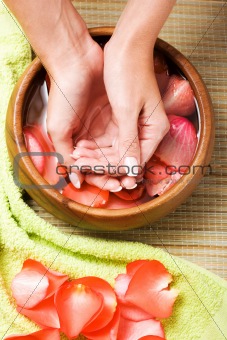 Hands in bowl of water with petals
