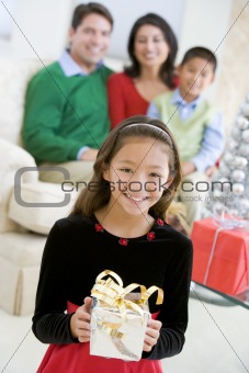 Young Girl Standing Holding Christmas Present,With Her Parents A
