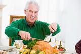 Man Carving Up Turkey At Christmas Dinner