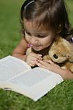 Young girl outside in the park reading a book