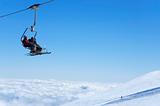 Chair lift with skiers above the clouds