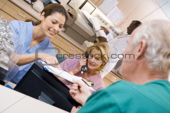 Nurses Discussing A Clipboard At The Reception Area In A Hospita
