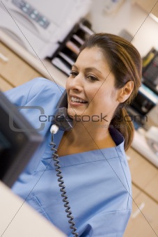 A Nurse On The Telephone At The Reception Area In A Hospital