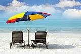 wooden chairs and colorful umbrella on sand beach