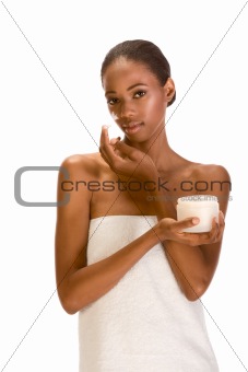 Afro-American girl wrapped in towel putting cream on face