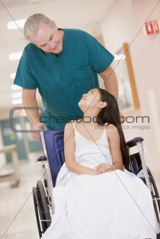 An Orderly Pushing A Little Girl In A Wheelchair Down A Hospital