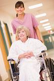 A Nurse Pushing A Senior Woman In A Wheelchair Down A Hospital C