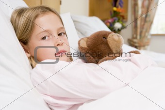 Young Girl Lying In Hospital Bed With Teddy Bear