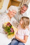 Granddaughter Giving Flowers To Her Grandmother In Hospital