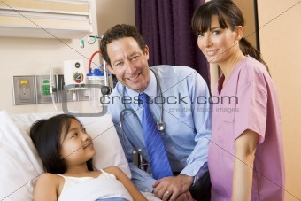 Doctor And Nurse Standing In Hospital Room With Young Girl