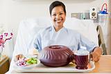 Woman Sitting In Hospital Bed With A Tray Of Food
