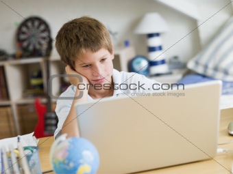Young Boy Using A Laptop In His Bedroom