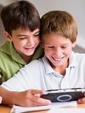 Two Young Boys Playing With A Handheld Video Game