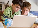 Two Young Boys Using A Laptop At Home