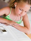 Young Girl Reading A Book While Listening To An MP3 Player
