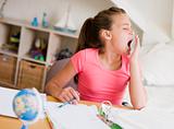 Young Girl Yawning, Doing Her Homework