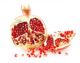 Pieces of a pomegranate and pomegranate grains. Over white.