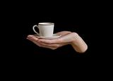female hand  keeps teacup on black background