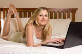 Woman on laptop on bed