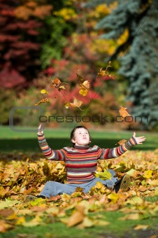 boy playing in fall leaves