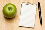 Pen, Paper and Apple on a Wood Background
