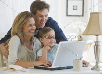 Mother and Father using a laptop with their daughter