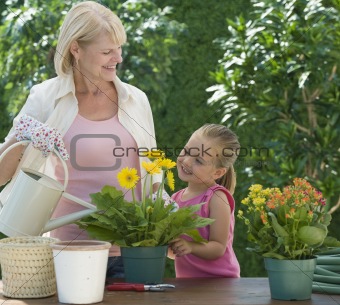 Grandmother and grand daughter watering plants