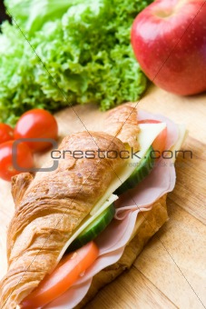 Fresh croissant with ham, cheese and salad