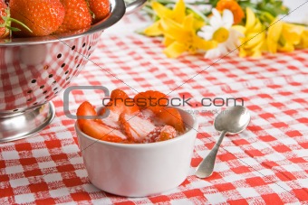 Sliced strawberries and cream in a white pot with flowers