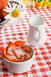 Sliced strawberries and cream in a white pot with a daisy