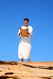man reading scroll in rocky desert land scape