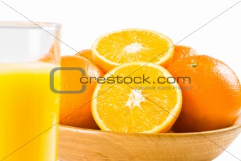 Oranges with a glass of orange juice in the foreground