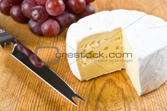 Segment of brie with grapes and a knife