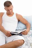 man lying on bed and reading book