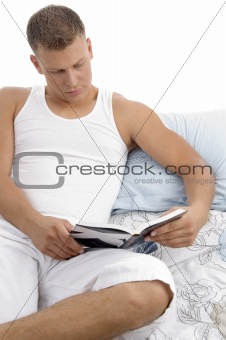 man lying on bed and reading book